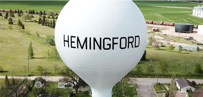 AdobeStock_436105265 4 An image looking up at a group of flagpoles flying a variety of flags with a sign in front of them.