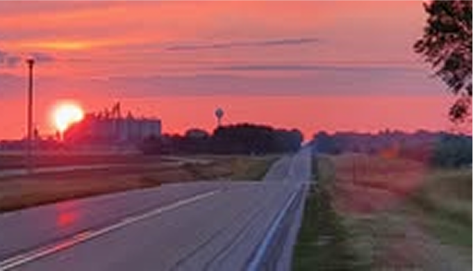 a road over slightly sloping hills taken at sunset