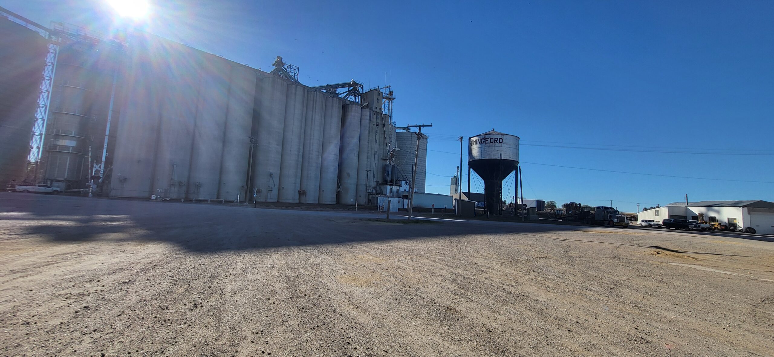 1000012653 An image looking up at a group of flagpoles flying a variety of flags with a sign in front of them.